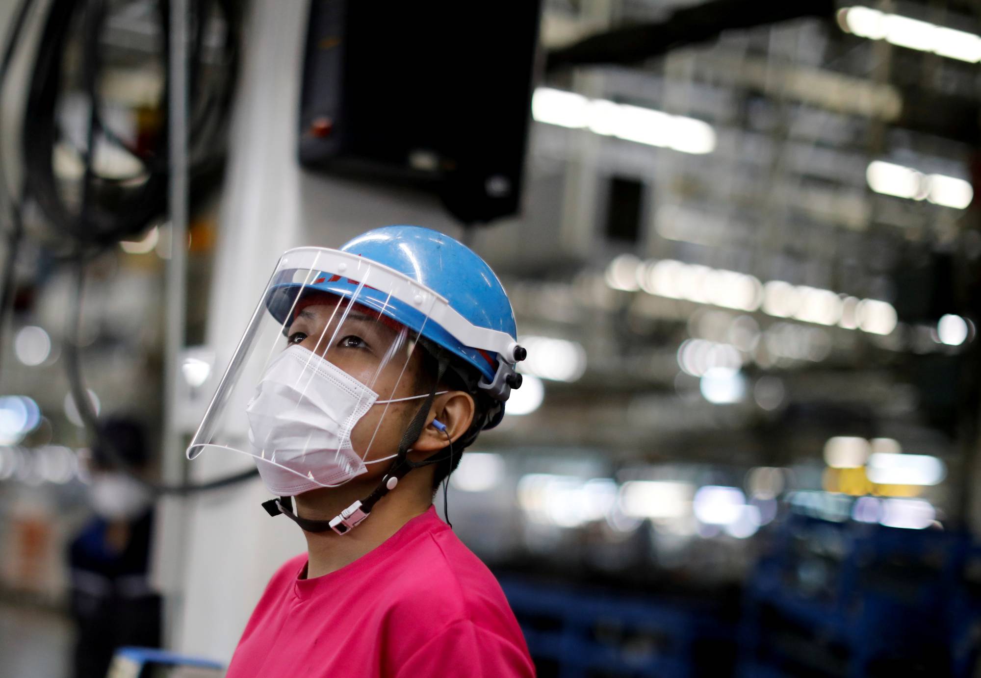 A worker at an automobile assembly line at the Mitsubishi Fuso Truck and Bus Corp. factory in Kawasaki takes protective measures against COVID-19. | REUTERS